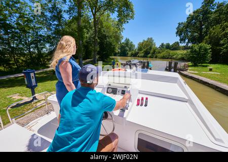 Ein junges Paar, das auf dem Canal du Midi durch eine Schleuse fährt. Der Canal du Midi ist als UNESCO-Weltkulturerbe eingetragen. Stockfoto