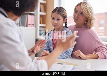 Porträt der kaukasischen Mutter und Tochter, die beim Arztbesuch in der Klinik dem Kinderarzt zuhören Stockfoto
