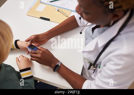 Draufsicht einer Ärztin zur Messung der Sauerstoffsättigung des Kindes mit Pulsoxymeter Stockfoto