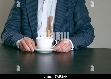 Ein nicht erkennbarer Mann verschüttete Kaffee oder Tee auf ein weißes Hemd. Daily Life Flin Concept. Stockfoto