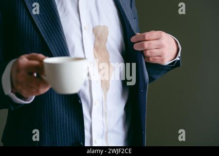 Ein nicht erkennbarer Mann verschüttete Kaffee oder Tee auf ein weißes Hemd. Daily Life Flin Concept. Stockfoto