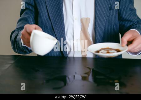 Ein Mann in einem Anzug verschüttete Kaffee auf ein weißes Hemd im Café. Dreckiger brauner Kaffeefleck auf der Kleidung. Daily Life Flin Concept. Stockfoto