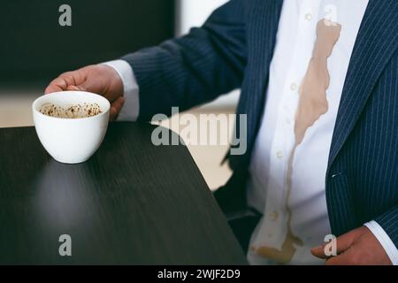 Ein nicht erkennbarer Mann verschüttete Kaffee oder Tee auf ein weißes Hemd. Daily Life Flin Concept. Stockfoto