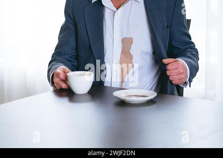 Ein nicht erkennbarer Mann verschüttete Kaffee oder Tee auf ein weißes Hemd. Daily Life Flin Concept. Stockfoto