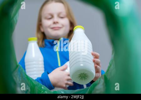 Niedriger Blickwinkel: Ein Kind sortiert den Papierkorb aus Kunststoff zu Hause. Nachhaltige und umweltbewusste Gesellschaft zum Schutz des Planetenkonzepts. Stockfoto