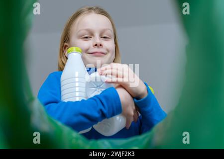 Niedriger Blickwinkel: Ein Kind sortiert den Papierkorb aus Kunststoff zu Hause. Nachhaltige und umweltbewusste Gesellschaft zum Schutz des Planetenkonzepts. Stockfoto