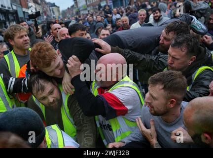 Atherstone, Großbritannien. Februar 2024. Ein Spieler versucht auf der Straße, über die Spitze des Scrum zu klettern, während er versucht, zum Ball zu gelangen. Die Spieler kommen zusammen, um das Atherstone Ball Game zu spielen. Das Spiel 2024 ist das 824. Und es geht auf das Jahr 1199 zurück. Spieler kämpfen auf der Straße um einen übergroßen Ball. Wer den Ball nach zwei Stunden in der Hand hat, gewinnt. Das Spiel ehrt ein Spiel zwischen Leicestershire und Warwickshire im Jahr 1199, bei dem die Teams eine Tasche Gold als Ball verwendeten. (Foto von Martin Pope/SOPA Images/SIPA USA) Credit: SIPA USA/Alamy Live News Stockfoto