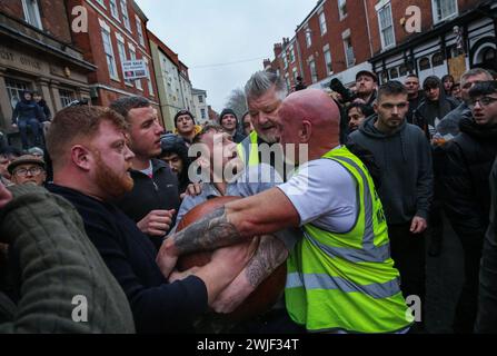 Atherstone, Großbritannien. Februar 2024. Spieler und Marshals kämpfen gegeneinander um den Ball. Die Spieler kommen zusammen, um das Atherstone Ball Game zu spielen. Das Spiel 2024 ist das 824. Und es geht auf das Jahr 1199 zurück. Spieler kämpfen auf der Straße um einen übergroßen Ball. Wer den Ball nach zwei Stunden in der Hand hat, gewinnt. Das Spiel ehrt ein Spiel zwischen Leicestershire und Warwickshire im Jahr 1199, bei dem die Teams eine Tasche Gold als Ball verwendeten. Quelle: SOPA Images Limited/Alamy Live News Stockfoto