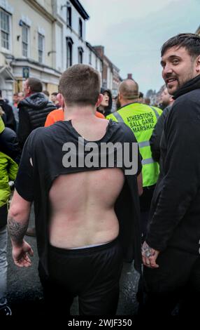 Atherstone, Großbritannien. Februar 2024. Ein Spieler taucht aus einem Scrum auf, sein Hemd ist fast abgerissen. Die Spieler kommen zusammen, um das Atherstone Ball Game zu spielen. Das Spiel 2024 ist das 824. Und es geht auf das Jahr 1199 zurück. Spieler kämpfen auf der Straße um einen übergroßen Ball. Wer den Ball nach zwei Stunden in der Hand hat, gewinnt. Das Spiel ehrt ein Spiel zwischen Leicestershire und Warwickshire im Jahr 1199, bei dem die Teams eine Tasche Gold als Ball verwendeten. Quelle: SOPA Images Limited/Alamy Live News Stockfoto