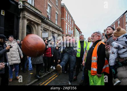 Atherstone, Großbritannien. Februar 2024. Ein Spieler wirft den Ball während des Spiels zurück ins Spiel. Die Spieler kommen zusammen, um das Atherstone Ball Game zu spielen. Das Spiel 2024 ist das 824. Und es geht auf das Jahr 1199 zurück. Spieler kämpfen auf der Straße um einen übergroßen Ball. Wer den Ball nach zwei Stunden in der Hand hat, gewinnt. Das Spiel ehrt ein Spiel zwischen Leicestershire und Warwickshire im Jahr 1199, bei dem die Teams eine Tasche Gold als Ball verwendeten. Quelle: SOPA Images Limited/Alamy Live News Stockfoto