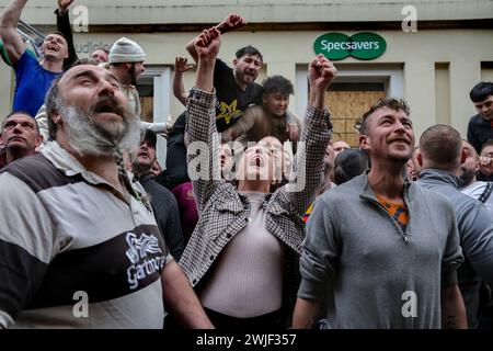 Atherstone, Großbritannien. Februar 2024. Die Spieler schreien und verlangen, dass der Ball aus dem Fenster geworfen wird, während sie auf den Spielbeginn warten. Die Spieler kommen zusammen, um das Atherstone Ball Game zu spielen. Das Spiel 2024 ist das 824. Und es geht auf das Jahr 1199 zurück. Spieler kämpfen auf der Straße um einen übergroßen Ball. Wer den Ball nach zwei Stunden in der Hand hat, gewinnt. Das Spiel ehrt ein Spiel zwischen Leicestershire und Warwickshire im Jahr 1199, bei dem die Teams eine Tasche Gold als Ball verwendeten. Quelle: SOPA Images Limited/Alamy Live News Stockfoto