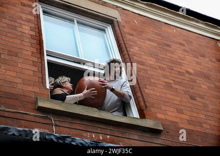 Atherstone, Großbritannien. Februar 2024. Der Match Ball erscheint am Fenster, bevor er zu den Spielern unten geworfen wird. Die Spieler kommen zusammen, um das Atherstone Ball Game zu spielen. Das Spiel 2024 ist das 824. Und es geht auf das Jahr 1199 zurück. Spieler kämpfen auf der Straße um einen übergroßen Ball. Wer den Ball nach zwei Stunden in der Hand hat, gewinnt. Das Spiel ehrt ein Spiel zwischen Leicestershire und Warwickshire im Jahr 1199, bei dem die Teams eine Tasche Gold als Ball verwendeten. Quelle: SOPA Images Limited/Alamy Live News Stockfoto