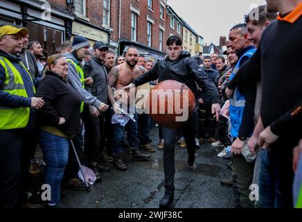 Atherstone, Großbritannien. Februar 2024. Ein Spieler wirft den Ball während des Spiels zurück ins Spiel. Die Spieler kommen zusammen, um das Atherstone Ball Game zu spielen. Das Spiel 2024 ist das 824. Und es geht auf das Jahr 1199 zurück. Spieler kämpfen auf der Straße um einen übergroßen Ball. Wer den Ball nach zwei Stunden in der Hand hat, gewinnt. Das Spiel ehrt ein Spiel zwischen Leicestershire und Warwickshire im Jahr 1199, bei dem die Teams eine Tasche Gold als Ball verwendeten. Quelle: SOPA Images Limited/Alamy Live News Stockfoto