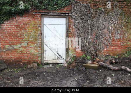 Eine alte Holztür in einem ummauerten Garten am West Horsley Place (Button House), Surrey, England, Großbritannien, Februar 2024 Stockfoto