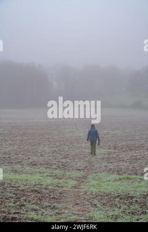Person, die einen Fußweg über Frost- und Nebelfelder rund um Stock, Essex, führt Stockfoto