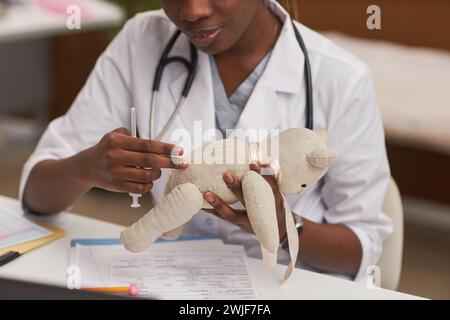Nahaufnahme eines Kinderarztes, der die Antibiotikainjektion mit Spielzeugbären erklärt, Kopierraum Stockfoto