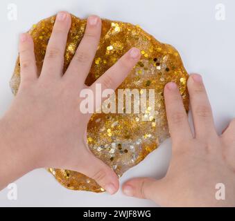 Kinder spielen mit goldenem Schleim Makro Nahansicht isoliert Stockfoto