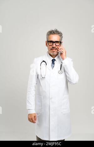 In diesem Porträt führt der reife Arzt einen Telefonanruf durch, bei dem er möglicherweise die Patientenversorgung diskutiert und die Bedeutung der Barrierefreiheit in der Medizin betont. Stockfoto