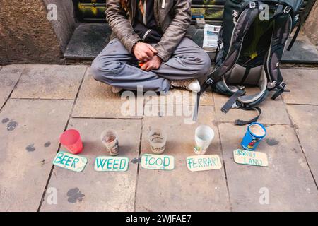 Armer Mann. Obdachloser Bettler, der Almosen um Essen, Bier, Gras, Ferrari, Disneyland bettelt. Hippie obdachlos. Stockfoto