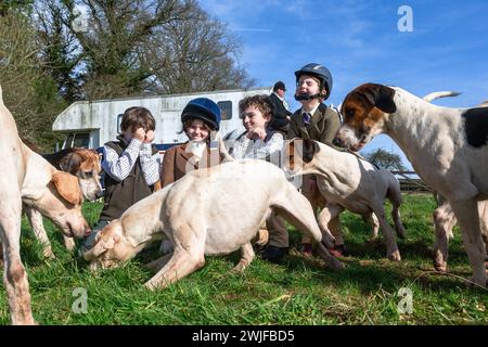 Arley, Worcestershire, Großbritannien. Februar 2024. Lokale Kinder, die während der Halbzeit nicht in der Schule sind, begrüßen die Hunde in einem Rasentreffen der Albrighton and Woodland Hunt in Arley, Worcestershire, an einem ungewöhnlich warmen Tag. Ein Rasentreffen geht normalerweise einer Jagd voraus. Quelle: Peter Lopeman/Alamy Live News Stockfoto