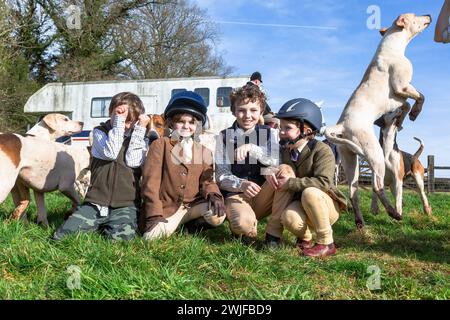 Arley, Worcestershire, Großbritannien. Februar 2024. Lokale Kinder, die während der Halbzeit nicht in der Schule sind, begrüßen die Hunde in einem Rasentreffen der Albrighton and Woodland Hunt in Arley, Worcestershire, an einem ungewöhnlich warmen Tag. Ein Rasentreffen geht normalerweise einer Jagd voraus. Quelle: Peter Lopeman/Alamy Live News Stockfoto