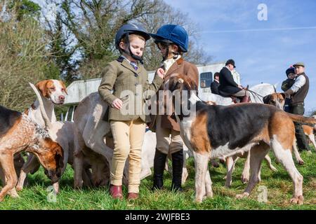 Arley, Worcestershire, Großbritannien. Februar 2024. Die vierjährige Myla Mills und ihre Freundin Rosa, die während der Halbzeit nicht in der Schule sind, begrüßen die Hunde in einem Rasentreffen der Albrighton and Woodland Hunt in Arley, Worcestershire, an einem ungewöhnlich warmen Tag. Ein Rasentreffen geht normalerweise einer Jagd voraus und findet auf privatem Gelände statt. Quelle: Peter Lopeman/Alamy Live News Stockfoto