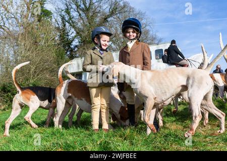 Arley, Worcestershire, Großbritannien. Februar 2024. Die vierjährige Myla Mills und ihre Freundin Rosa, die während der Halbzeit nicht in der Schule sind, begrüßen die Hunde in einem Rasentreffen der Albrighton and Woodland Hunt in Arley, Worcestershire, an einem ungewöhnlich warmen Tag. Ein Rasentreffen geht normalerweise einer Jagd voraus und findet auf privatem Gelände statt. Quelle: Peter Lopeman/Alamy Live News Stockfoto