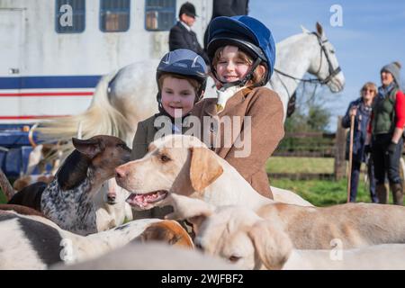 Arley, Worcestershire, Großbritannien. Februar 2024. Die vierjährige Myla Mills und ihre Freundin Rosa, die während der Halbzeit nicht in der Schule sind, begrüßen die Hunde in einem Rasentreffen der Albrighton and Woodland Hunt in Arley, Worcestershire, an einem ungewöhnlich warmen Tag. Ein Rasentreffen geht normalerweise einer Jagd voraus und findet auf privatem Gelände statt. Quelle: Peter Lopeman/Alamy Live News Stockfoto