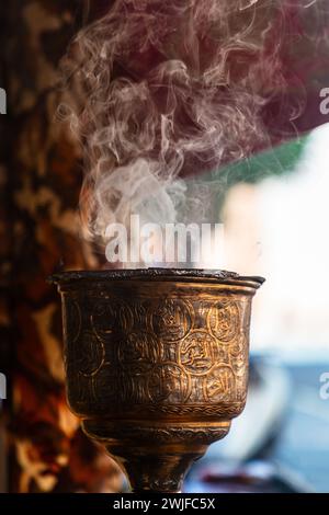 Weihrauchbrenner in Metall, Becherform, Zierrauchbrenner im arabischen Souk in Oman. Nahaufnahme mit Fokus auf Rauch. Stockfoto