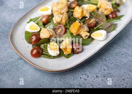 Warmer Salat mit Raps (Schnecken), Tomaten, Gurken, Blattgemüse, Wachteleiern und Olivenöl. Traditioneller Salat mit Meeresfrüchten. Nahaufnahme, selektiver Fokus. Stockfoto