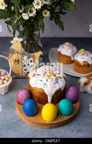 Osterkulich mit kandierten Früchten in weißer Glasur mit bunten Streuseln und bemalten Eiern. Traditionelles Ostergebäck. Osterferien. Nahaufnahme, wählen Sie Stockfoto