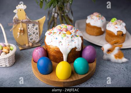 Osterkulich mit kandierten Früchten in weißer Glasur mit bunten Streuseln und bemalten Eiern. Traditionelles Ostergebäck. Osterferien. Nahaufnahme, wählen Sie Stockfoto