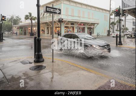 Eine Straße in Key West, Florida, nach einem tropischen Sturm. Die Straße ist überflutet und ein Auto fährt durch das Wasser und spritzt Wasser Stockfoto