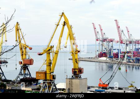 Industriecontainer Cargo Frachtschiff mit funktionierender Kranbrücke in der Werft in der Dämmerung für logistischen Import Export Hintergrund. Stockfoto