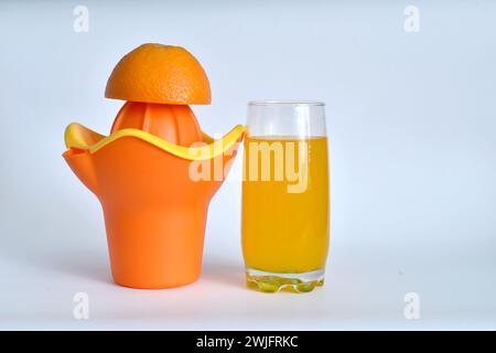 Gesunder Lebensstil. Auf einem weißen Tisch befinden sich ein manueller Entsafter und ein Glas frischen Saft. Stockfoto