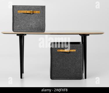 Moderne Büroeinrichtung mit modernen grauen Filzboxen mit braunen Ledergriffen auf minimalistischem Schreibtisch auf weißem Hintergrund Stockfoto