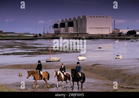 Barrow-in-Furness Ship Building 1980s UK. Kinder, die auf ihren Ponys über die Mündung des Flusses Duddonis Vickers Shipbuilding and Engineering, Ltd (VSEL) reiten. Der riesige Schuppen wurde als Maggie’s Shed bekannt, (nach Margaret Thatcher) 1980er Barrow-in-Furness, Cumbria, England 80er HOMER SYKES Stockfoto