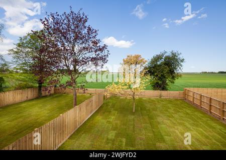 Cambridgeshire, England - 1. Mai 2018: Neu angelegte Rasenflächen und Landschaftsgärten brandneuer Häuser mit Blick auf die Landschaft. Stockfoto