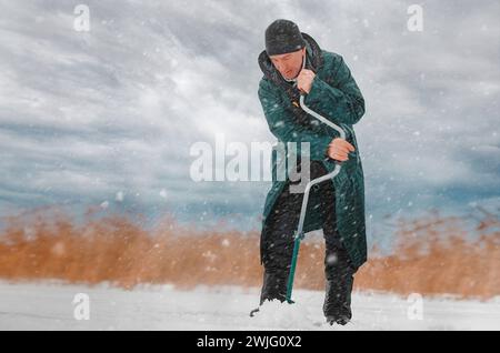 Ein Mann bohrt ein Loch ins Eis zum Angeln Stockfoto
