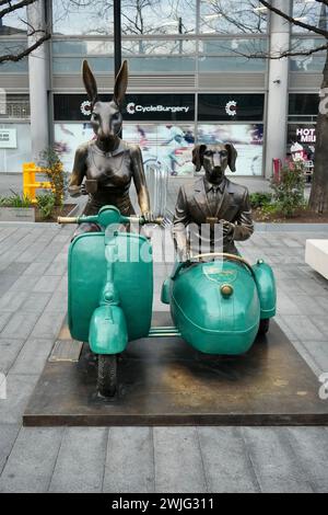 „Together Forever on Wheels“ eine Skulptur von Gillie und Marc mit Rabbitwoman und Dogman, Vespas und Kaffee. Spitalfields, London. Stockfoto