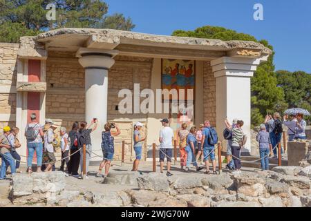 Palast von Minos, Knossos, Kreta, Griechenland. Eine Gruppe von Touristen, die das Fresko der „Prozession“ im südlichen Propylaeum bewundern. Stockfoto