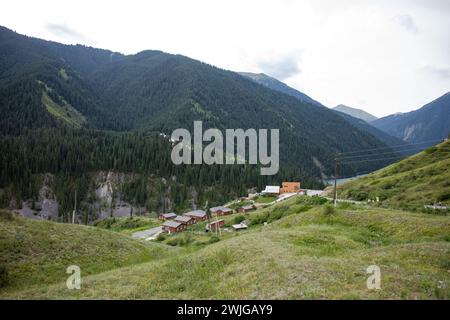 Traditionelles kirgisisches Jurtencamp im malerischen Bergtal in der Nähe des Flusses. Gemütliche Filz- und Holzjurten bieten lokale Gastfreundschaft inmitten von schneebedeckten Gipfeln. Stockfoto