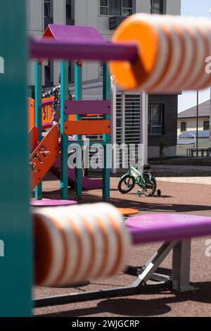 Lebendiger Spielplatz mit farbenfroher Rutsche, Treppen und Klettermöglichkeiten im Stadtgebiet mit umliegenden Wohngebäuden. Stockfoto
