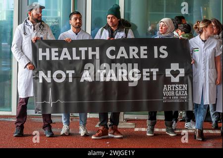 Den Haag, Niederlande. Februar 2024. Die Demonstranten halten während eines propalästinensischen Mittagsprotests ein Banner. Clival Servants, medizinische und Justizarbeiter in den Haag, hielten eine pro-palästinensische Mittagsproteste vor dem Eingang des Außenministeriums ab. Seit dem 7. Oktober startete Israel seine militärischen Angriffe auf den Gazastreifen, bei denen mehr als 28,400 Palästinenser, hauptsächlich Frauen und Kinder, getötet wurden, und mehr als 68.000 Verwundete seit Kriegsbeginn, so das von der Hamas betriebene gesundheitsministerium. Quelle: SOPA Images Limited/Alamy Live News Stockfoto