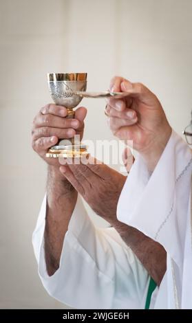 Nahaufnahme der Hände eines Priesters, der während einer katholischen Messe einen Wirt und Chalice hochhält. Stockfoto