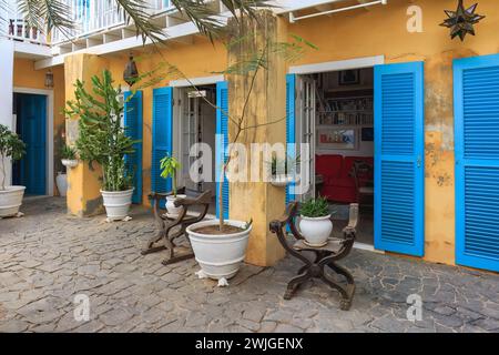 Boa Vista, Kap Verde - 22. März 2018: Ein gemütlicher Café-Garten in Sal Rei, mit rustikalen Holzmöbeln und leuchtenden blauen Fensterläden. Stockfoto