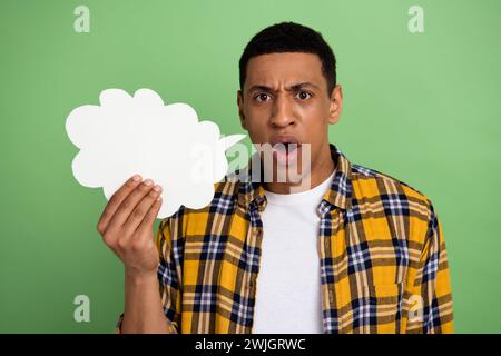 Foto des jungen Mannes tragen kariertes Hemd unzufrieden halten Luftblase Wolke aggressive Rede beeindruckt isoliert auf grünem Hintergrund Stockfoto