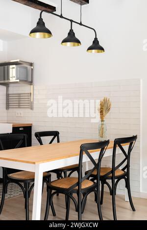 Das moderne Apartment ist ein Fragment eines stilvollen Wohnzimmers mit Stühlen und einem Esstisch im Loft-Stil mit dunklen Lampen. Einzigartiges Designkonzept für einen Stockfoto