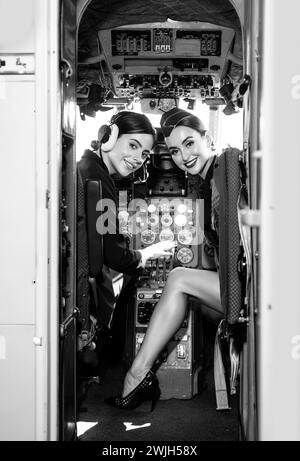 Zwei Piloteninnen lächeln und wünschen einen erfolgreichen Flug. Trainee Pilot und Fluglehrer in einem Flugzeug-Cockpit. Sie hält Aviator Headset und Stockfoto