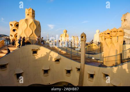 Dach der Casa Milà, La Pedrera, Touristen auf dem Dach, Terrassenschornsteine und Lüftungsschlitze bei Sonnenuntergang, moderne Architektur von Antoni Gaudí, Barcelona, Spanien Stockfoto